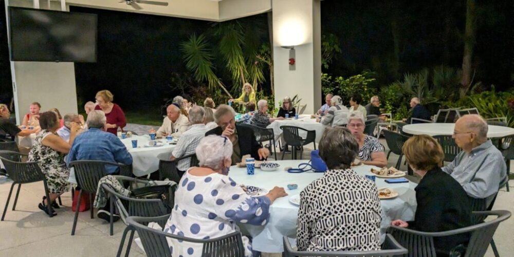 People enjoying a delicious meal outdoors under the pavilion, sharing laughter and good times in a relaxed, fun atmosphere.